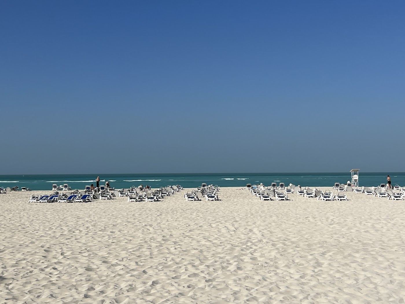 Pale natural sand and calm Gulf water on a beach in Abu Dhabi