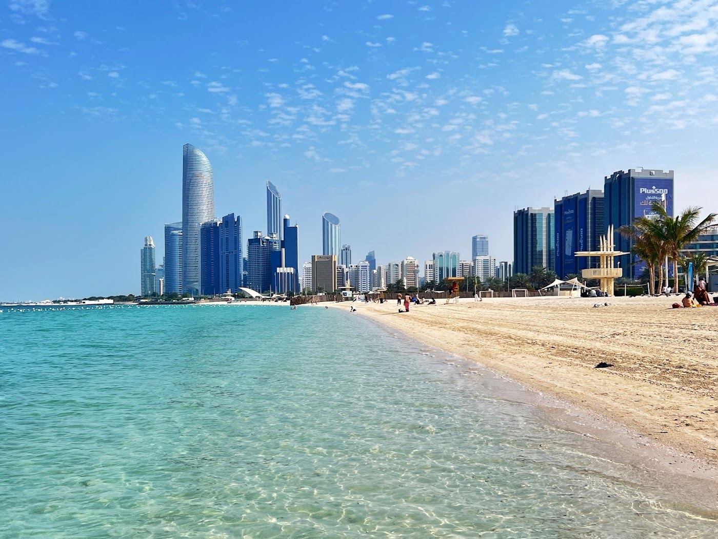 Calm clear water and white sand on the Abu Dhabi Corniche on a bright day