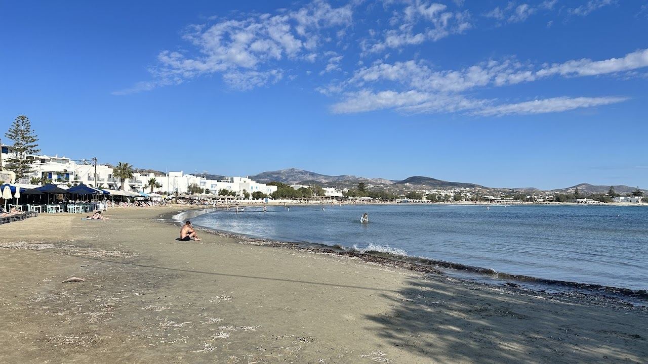 Rows of sunbeds and umbrellas on the dark sand of Agios Georgios Beach near Perivolos