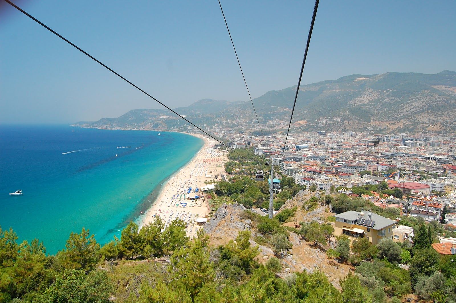 Lively central Alanya beach with golden sand and clear water below the town