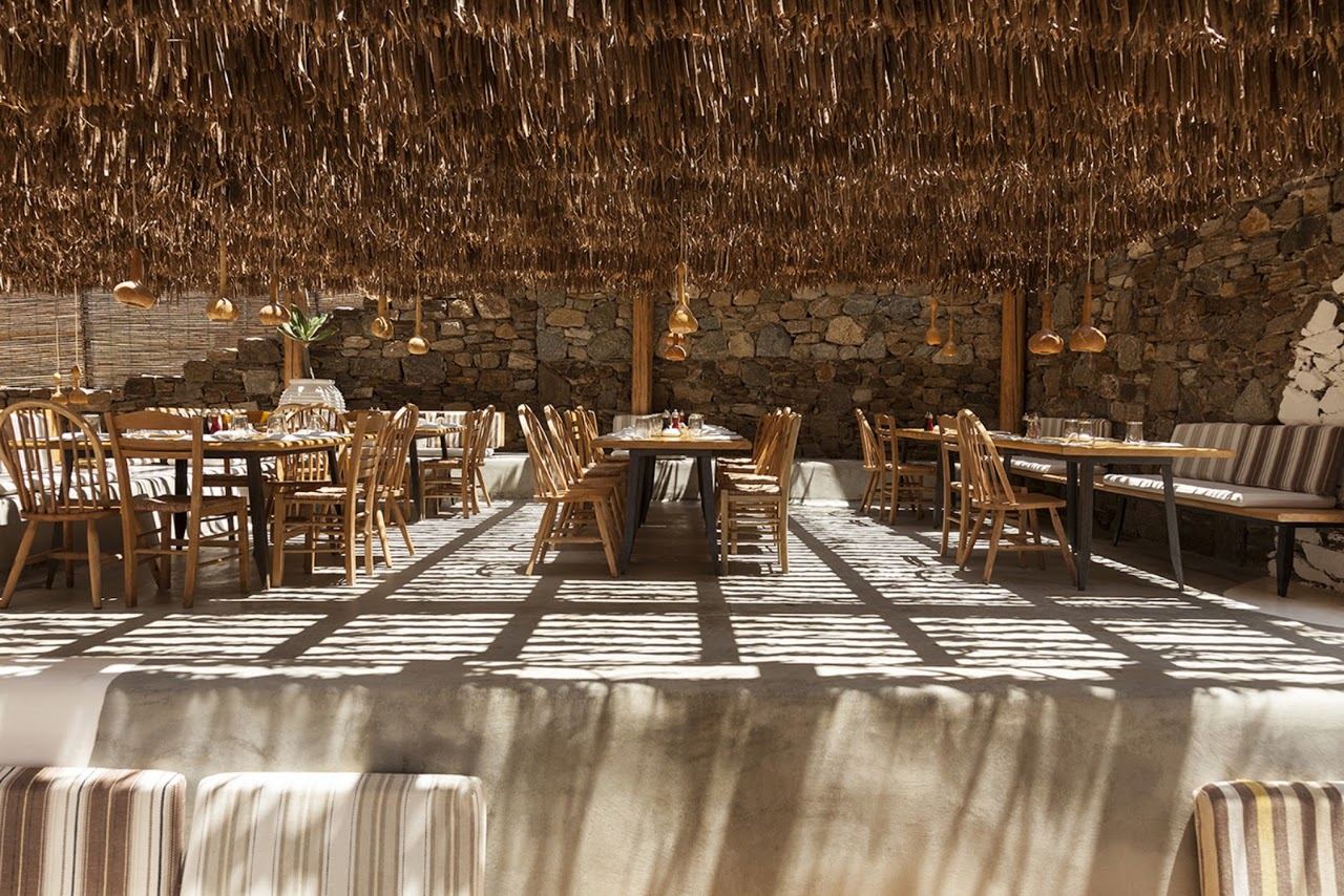 Thatched umbrellas and loungers of Alemagou beach bar on the sand at Ftelia, Mykonos