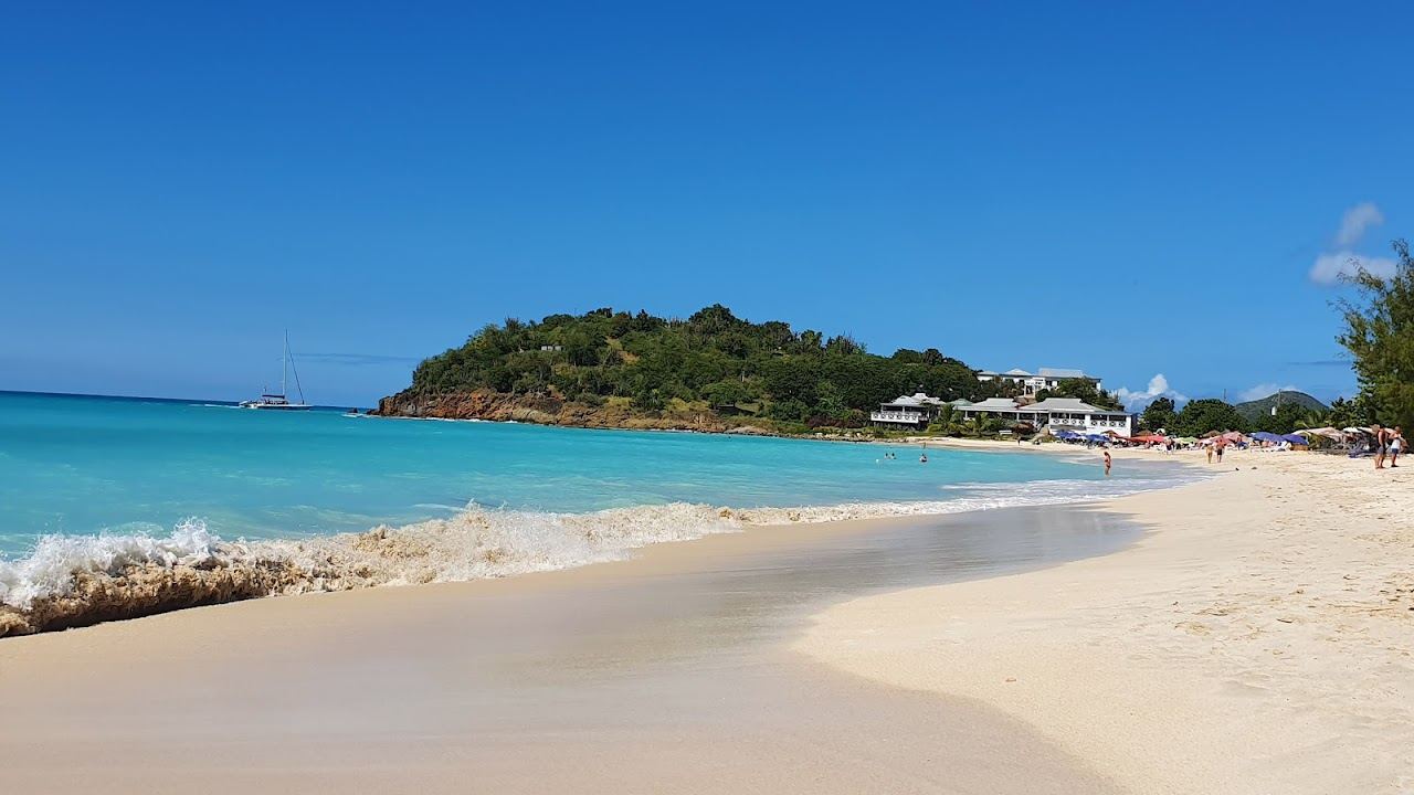 Wide golden sand and calm clear Caribbean water on the west coast sweep of Ffryes Beach in Antigua