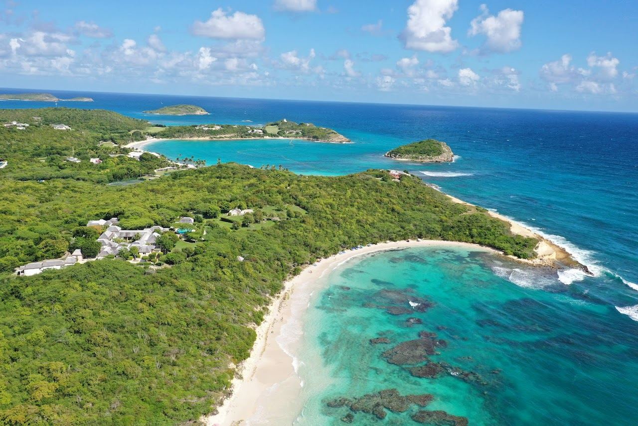 Wide pink tinged sand and white capped Atlantic water on the crescent of Half Moon Bay in Antigua