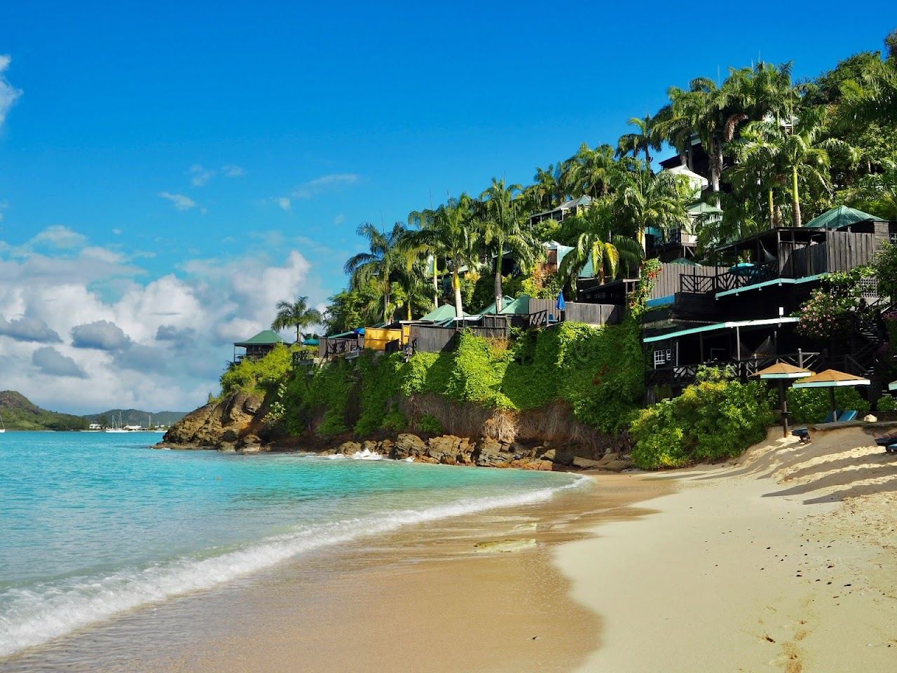 Calm shallow turquoise water and powdery white sand backed by palms at Valley Church Beach in Antigua