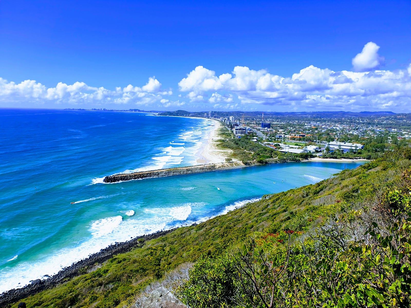 Surfers and swimmers below the headland reserve at Burleigh Heads on the Gold Coast in Australia