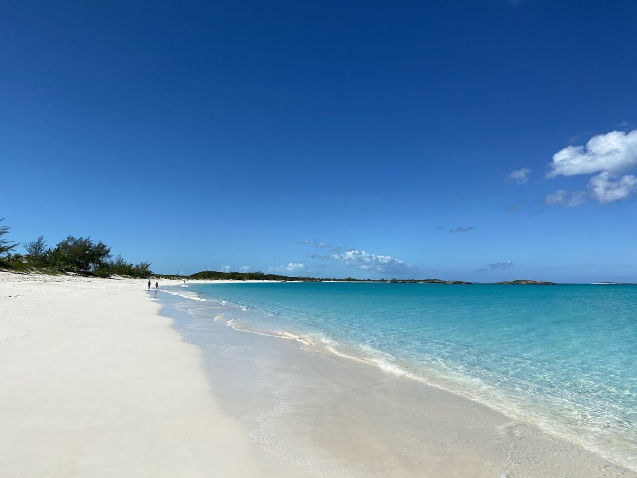 Calm clear turquoise water and pale sand on a Bahamian beach under a bright sky