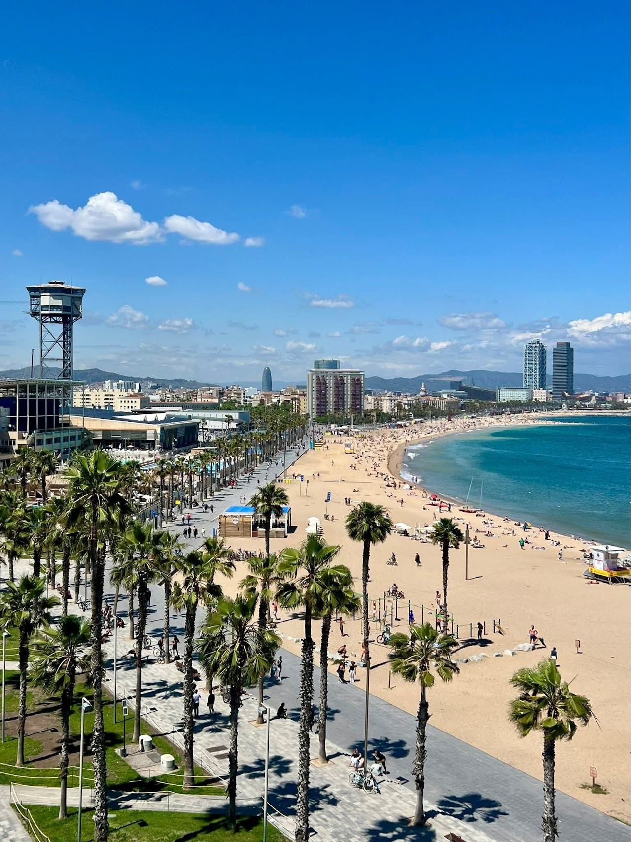 Golden afternoon light on the wide city sand and blue water of Barceloneta beach in Barcelona