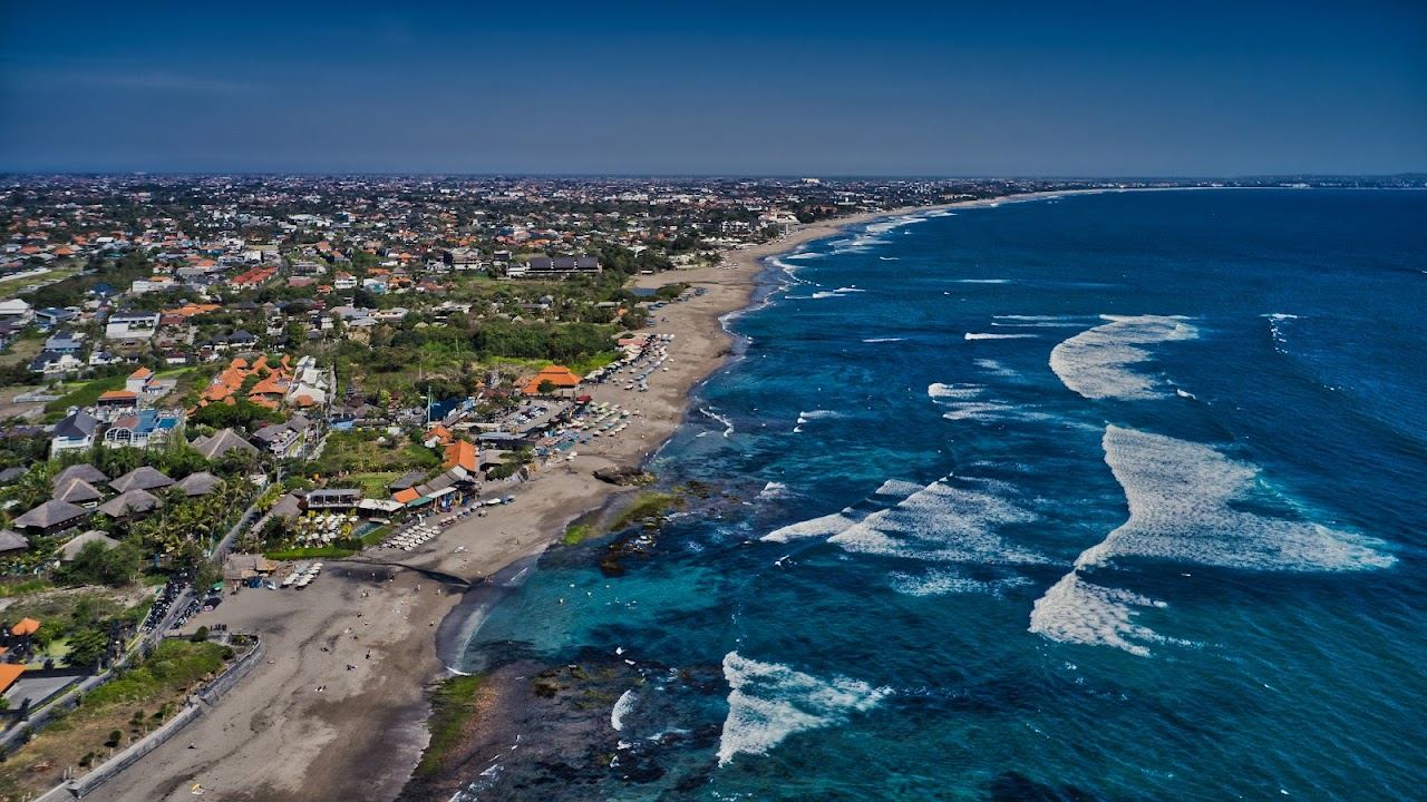 Surfers and beanbag bars on the dark sand at Canggu in Bali