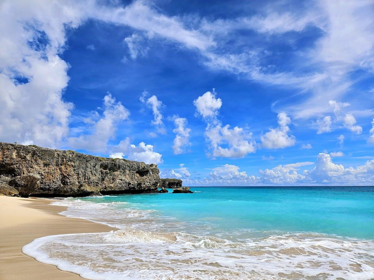 Palm framed white sand and rolling waves at Bottom Bay Barbados