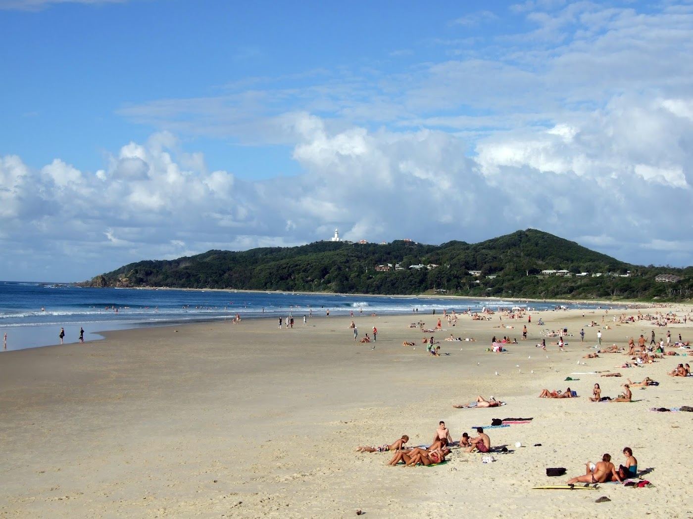 The wide curve of Main Beach at Byron Bay below the headland and lighthouse
