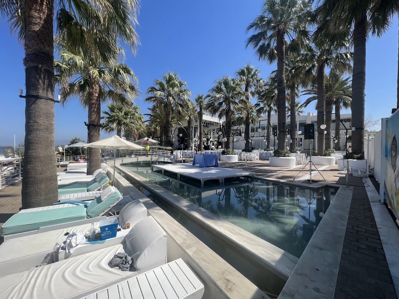 Cabanas and loungers arranged under palm trees at Cabana Mare Beach Club