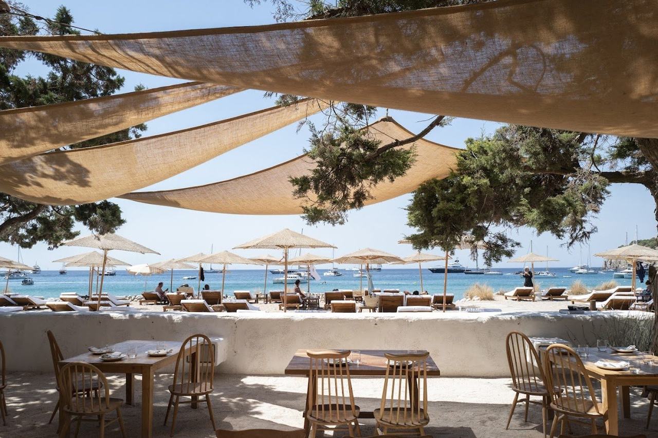 The clear water and pebble shore of Cala Jondal cove on the south coast of Ibiza with yachts offshore