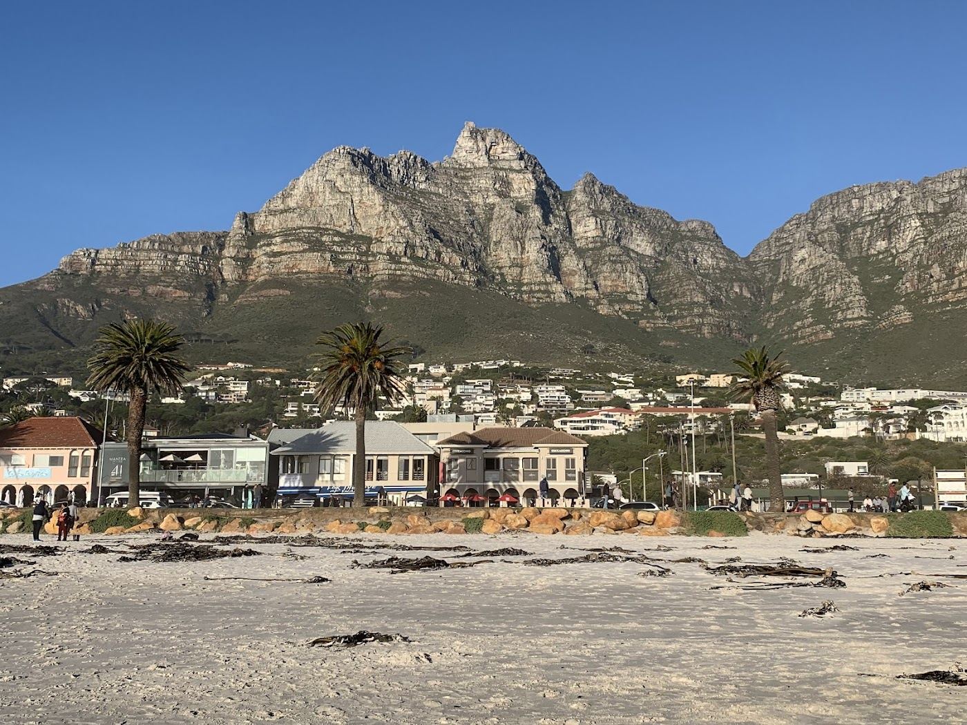 Surfers and beach front at Camps Bay below the Twelve Apostles in Cape Town