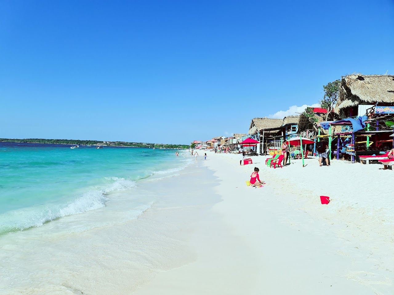 Palms leaning over bright white sand and clear turquoise water on Isla Baru near Cartagena