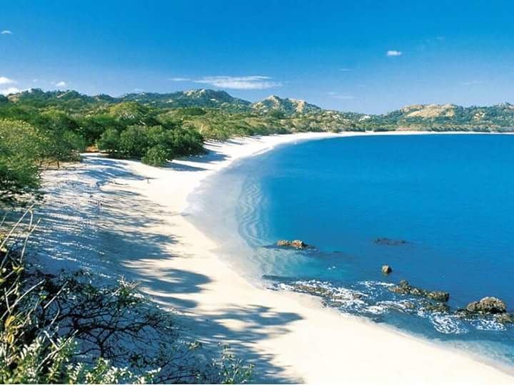 Golden light on the crushed shell sand and calm green water of Playa Conchal in Guanacaste, Costa Rica