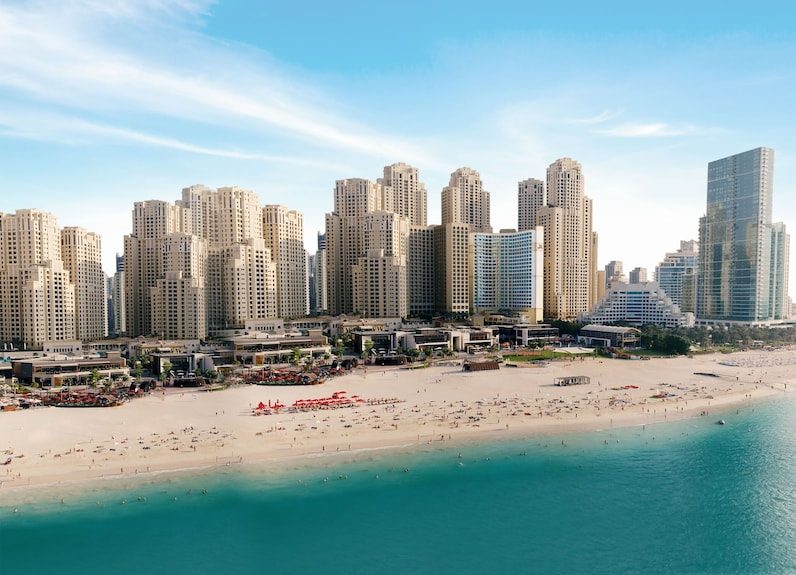 The manicured sand of a Dubai beach with skyscrapers rising directly behind