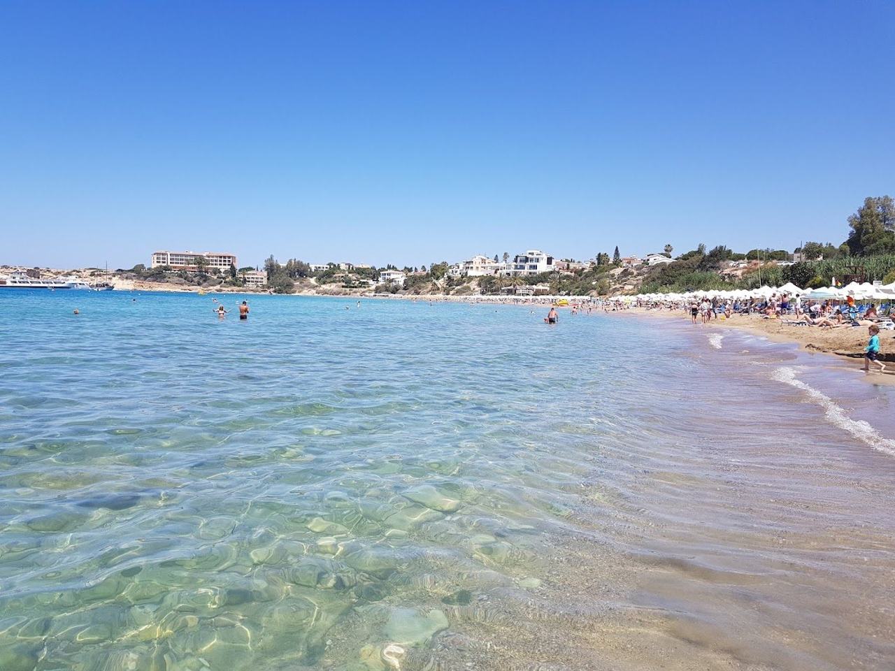 Sheltered sandy bay between two headlands with calm shallow turquoise water at Coral Bay near Paphos Cyprus