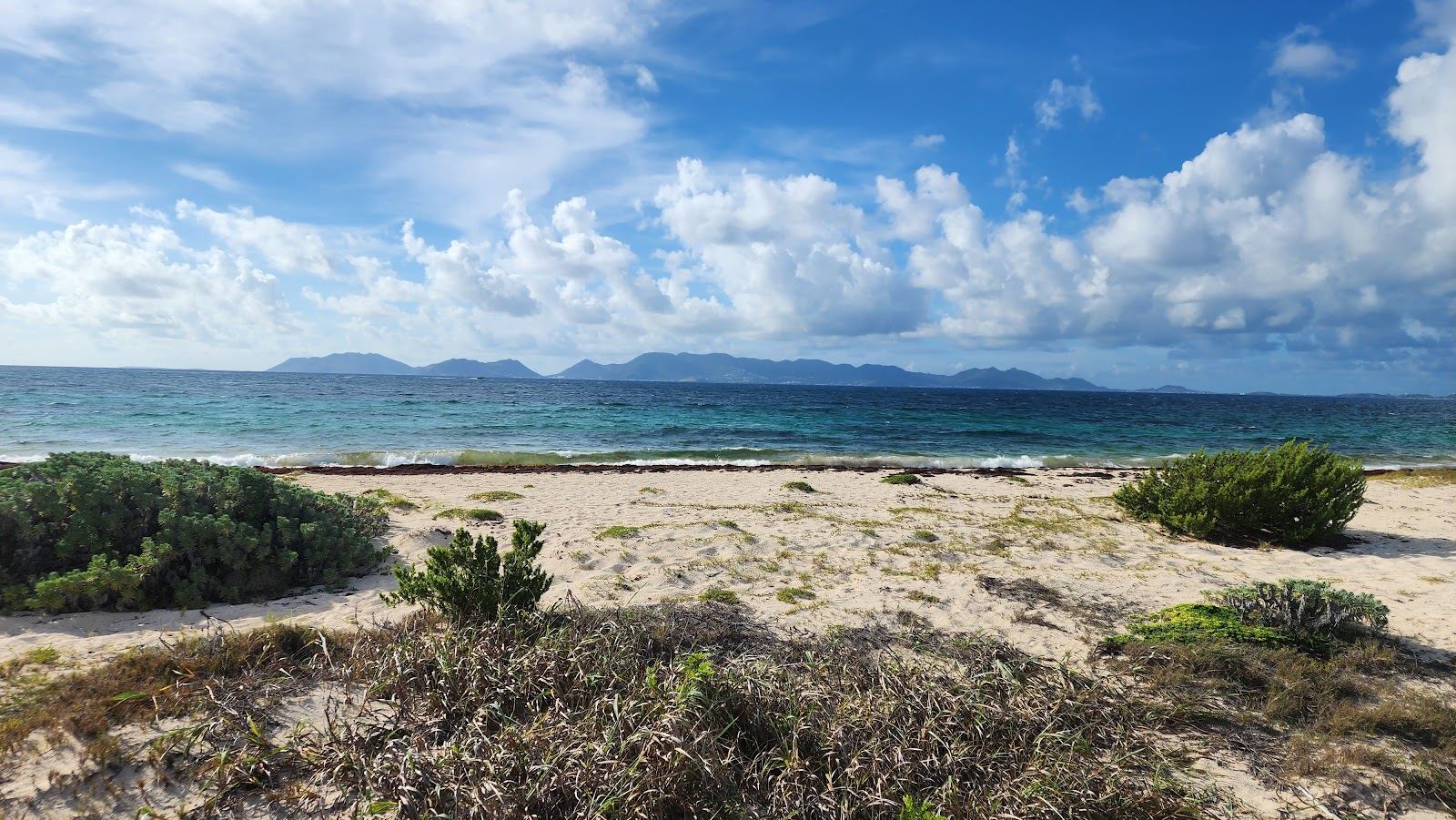 The long quiet white sand and shallow calm water of Cove Bay in Anguilla