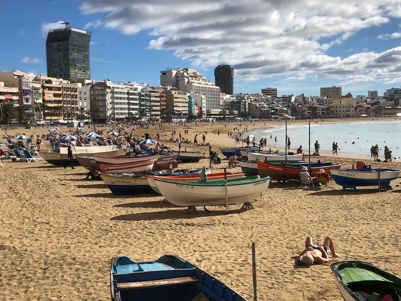 A long city beach with a cafe lined promenade and remote workers at Las Canteras in Gran Canaria