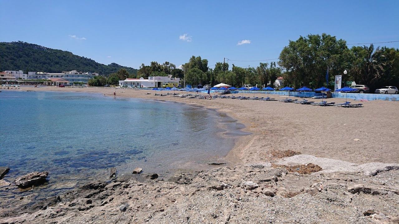 The long sandy sweep of Faliraki beach on Rhodes with calm blue water along the resort strip