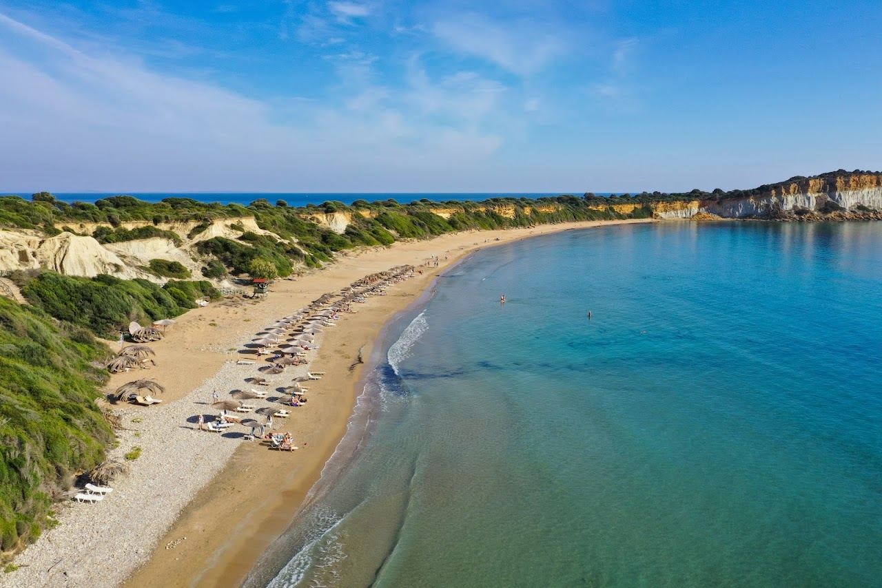 The curve of golden sand and shallow blue water at Gerakas beach below the clay cliffs on the Vassilikos peninsula of Zakynthos