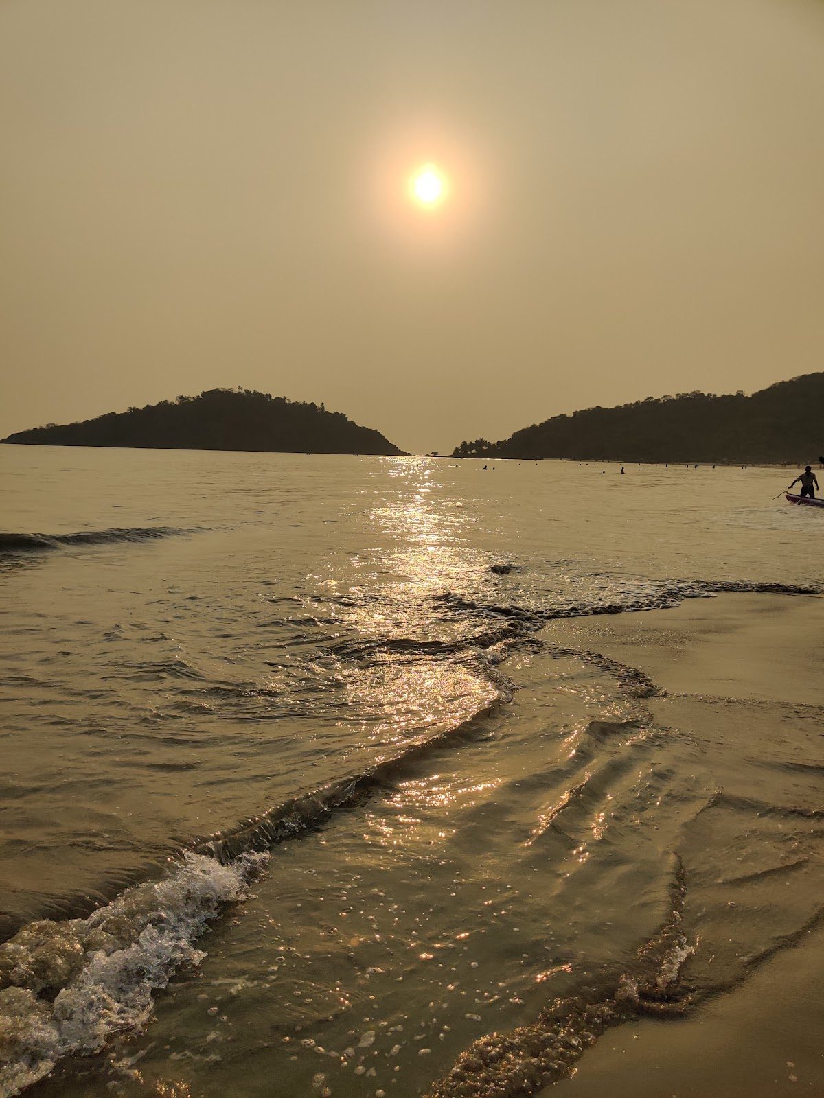 Golden sunset over the calm crescent bay and palms at Palolem in South Goa