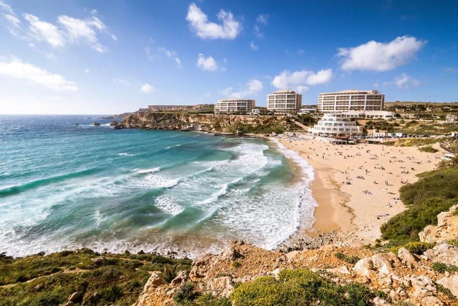 The wide golden sand crescent of Golden Bay in Malta backed by low cliffs