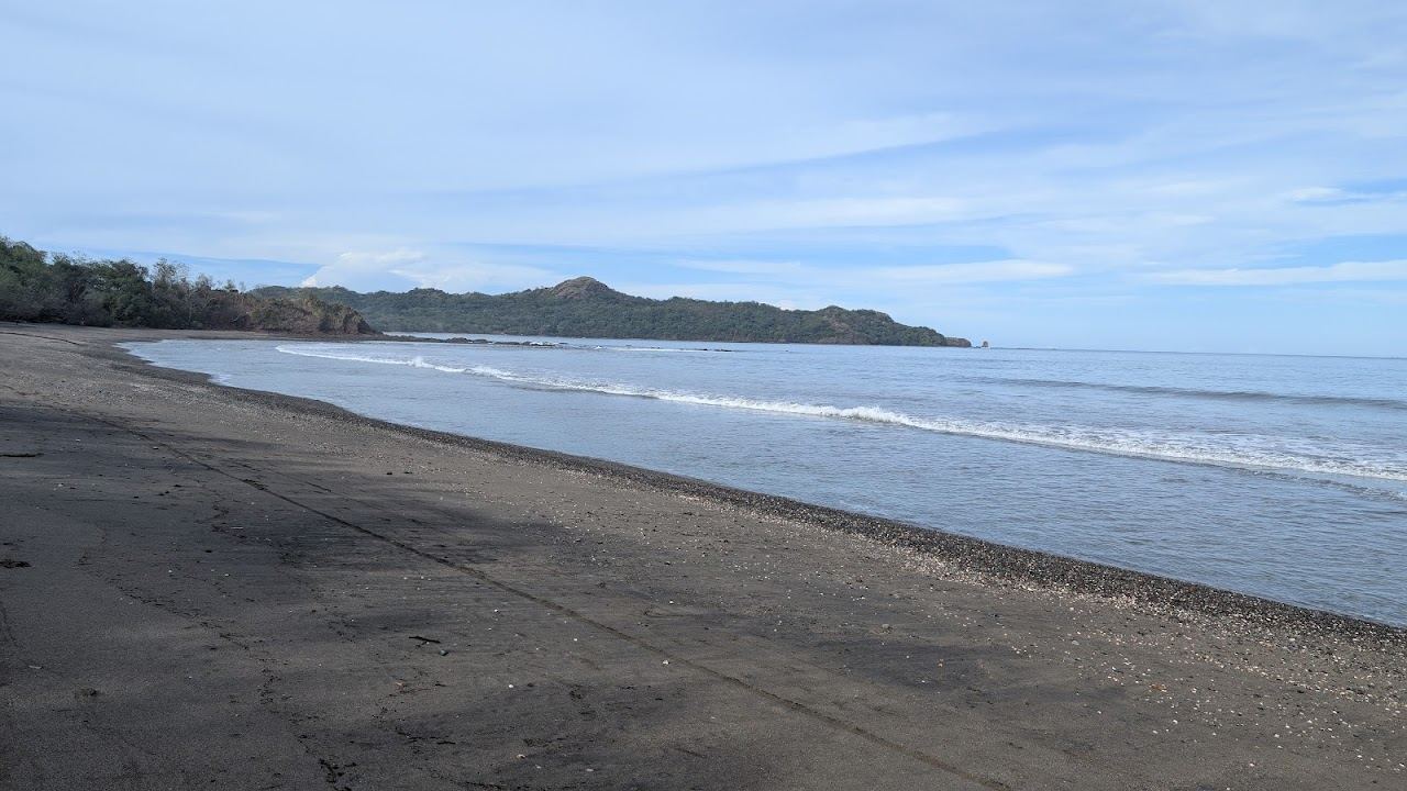 Calm clear turquoise water meeting pale sand on a sheltered Guanacaste beach