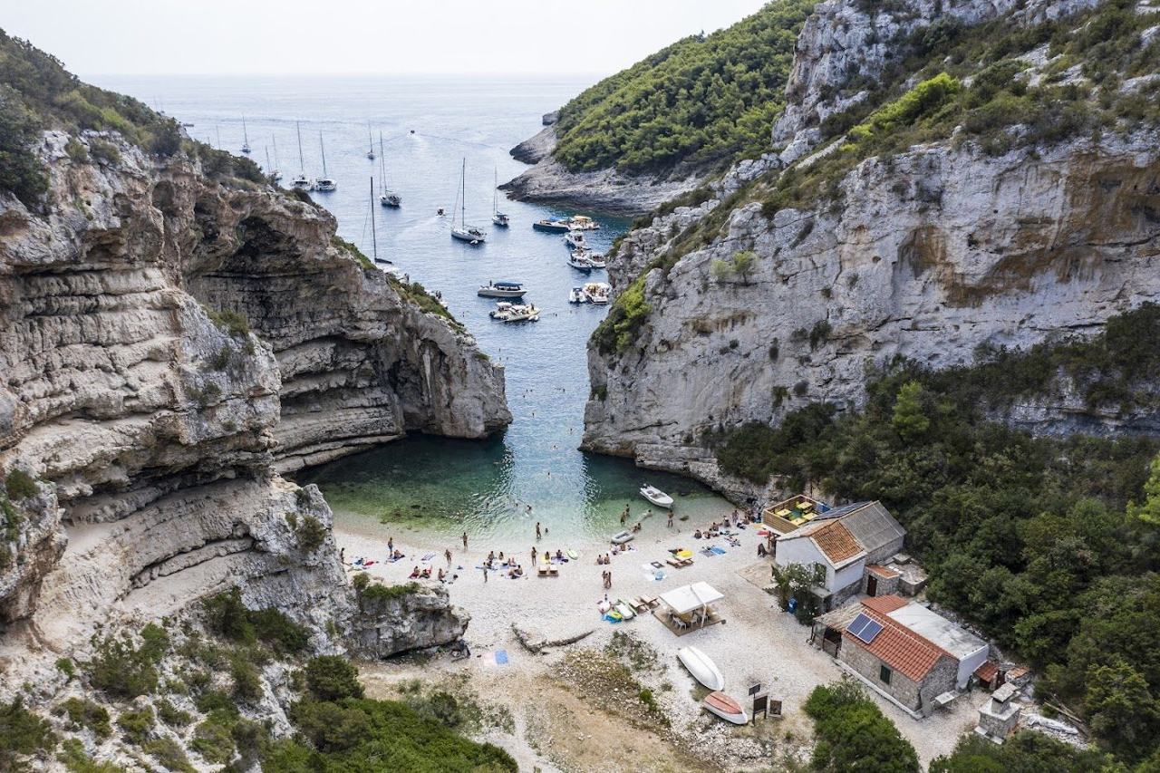 A near enclosed pebble inlet on remote Vis, where cliffs almost meet over a narrow turquoise mouth.