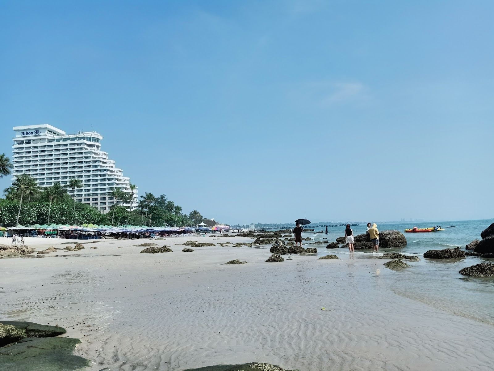 Calm shallow gulf water lapping the wide flat sand of Hua Hin Beach in Thailand.