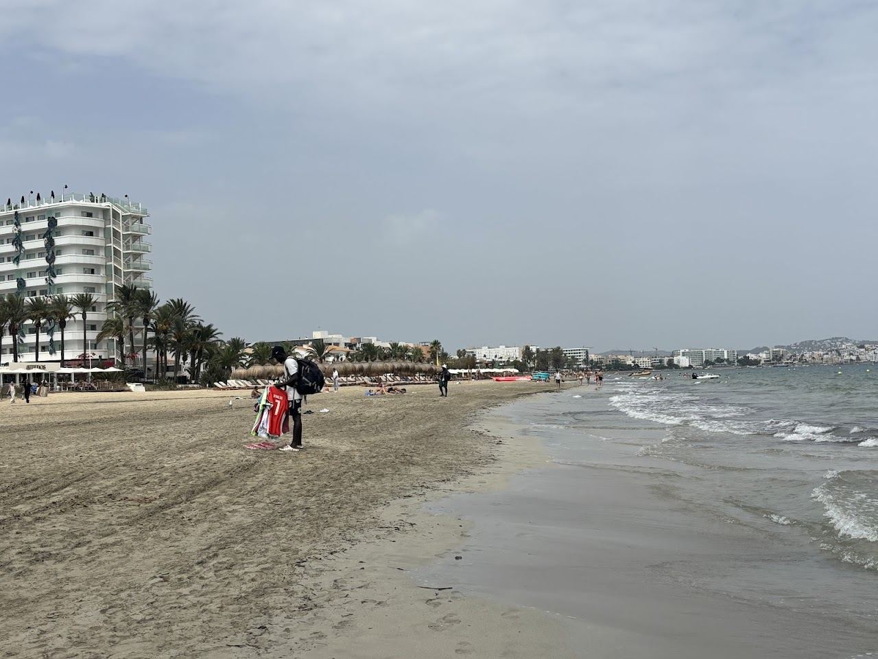 The long sand of Playa den Bossa in Ibiza lined with day clubs and sunbeds under a bright sky