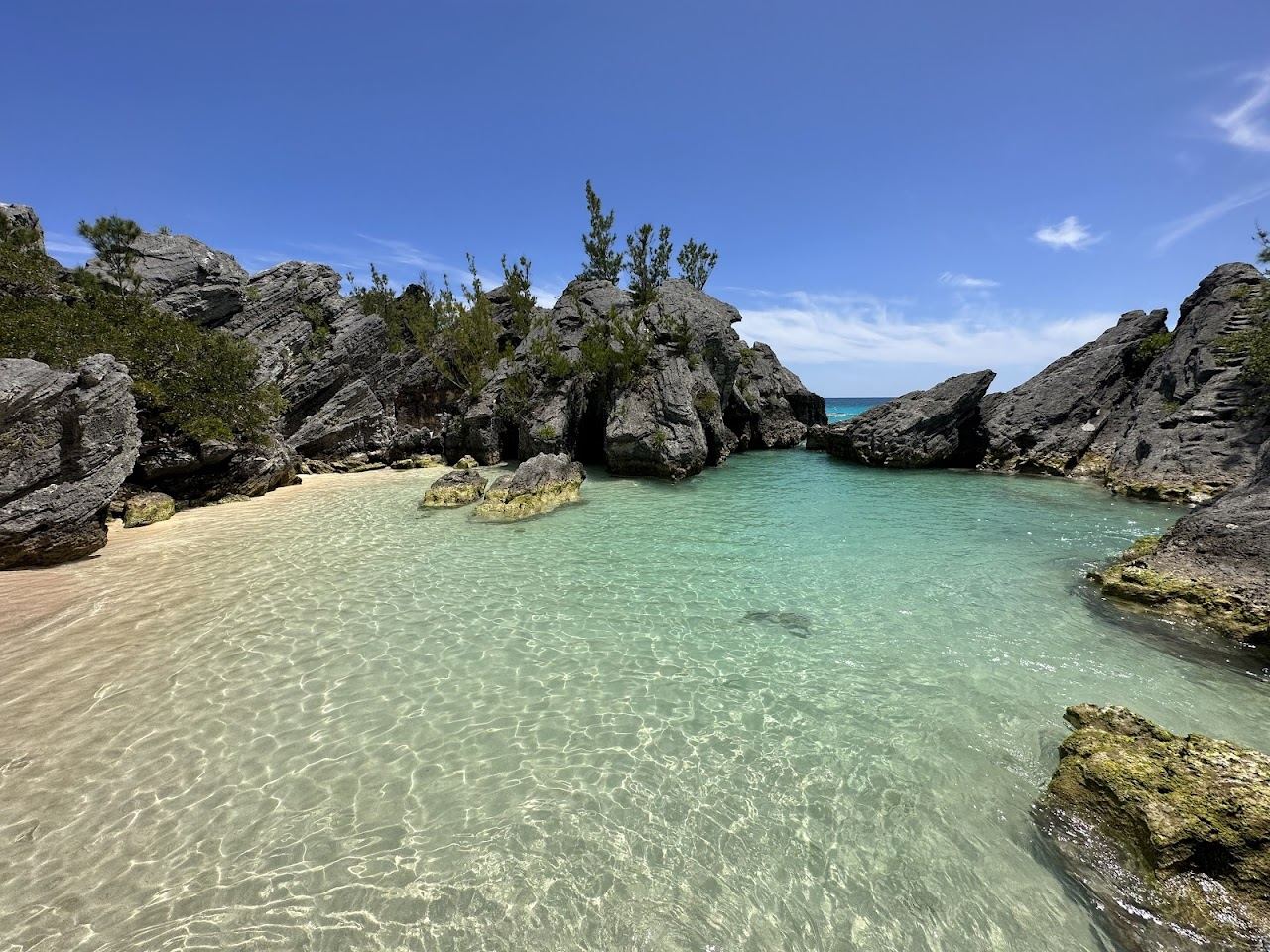 The calm shallow water and pink sand of the rock ringed lagoon at Jobsons Cove in Warwick, Bermuda