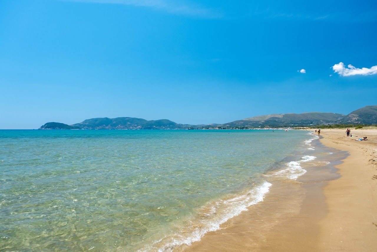 The wide golden sand and calm shallow water of Kalamaki beach in the marine park bay of Zakynthos