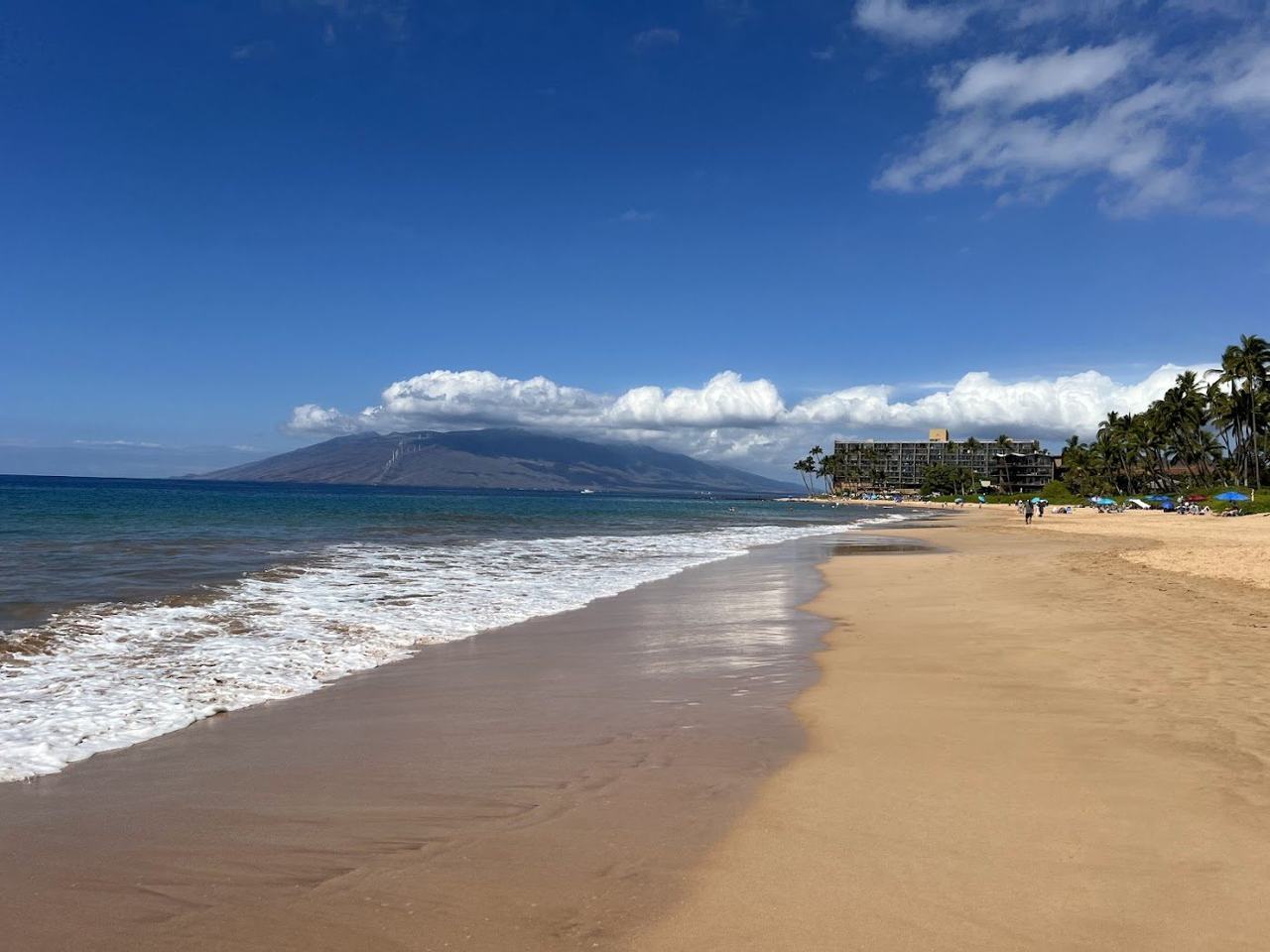Keawakapu Beach Kihei Maui a long stretch of fine golden sand with calm clear blue water and a low sun
