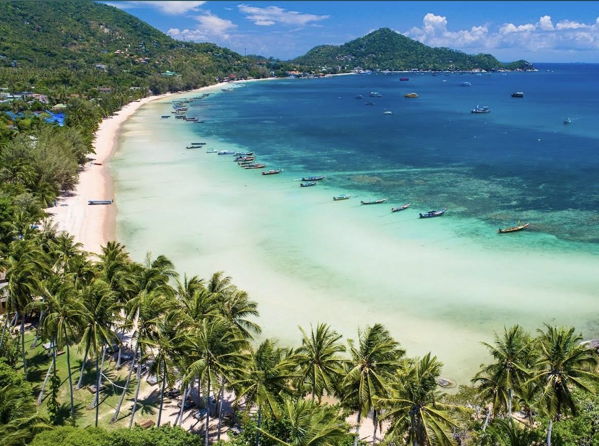 Palm backed golden sand and calm clear water along Sairee Beach on Koh Tao in Thailand