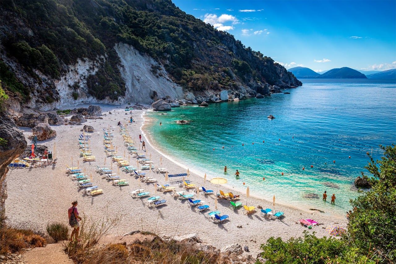 A hidden cove of clear turquoise water and pale sand backed by cliffs on Lefkada