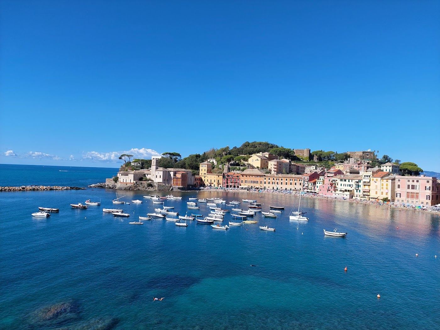 A calm sheltered sandy bay ringed by pastel houses at Sestri Levante in Liguria