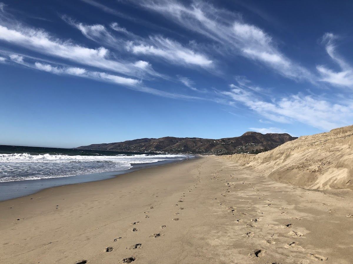 A wide California beach below low bluffs with surf rolling in along the Malibu coast.