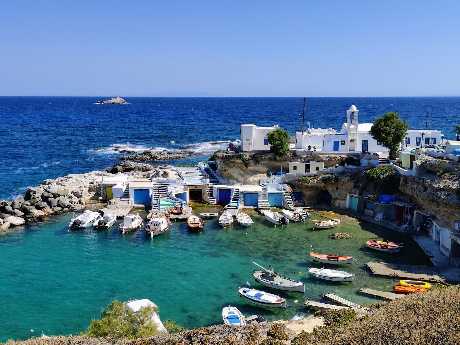 The small harbour of Mandrakia lined with whitewashed boat houses and clear water on the north coast of Milos