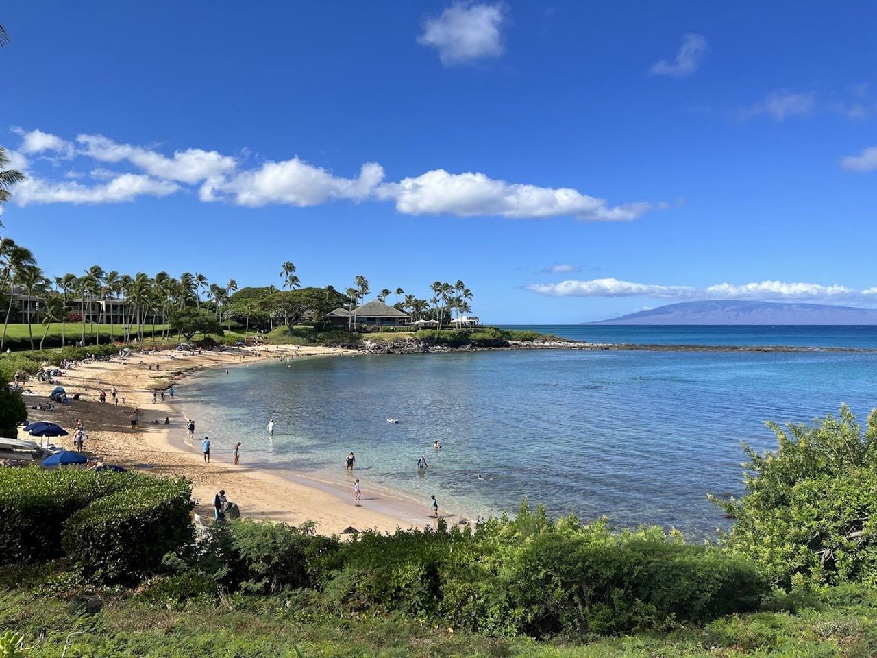 Clear calm turquoise water in a sheltered crescent bay ringed by rocky points on the west coast of Maui Hawaii