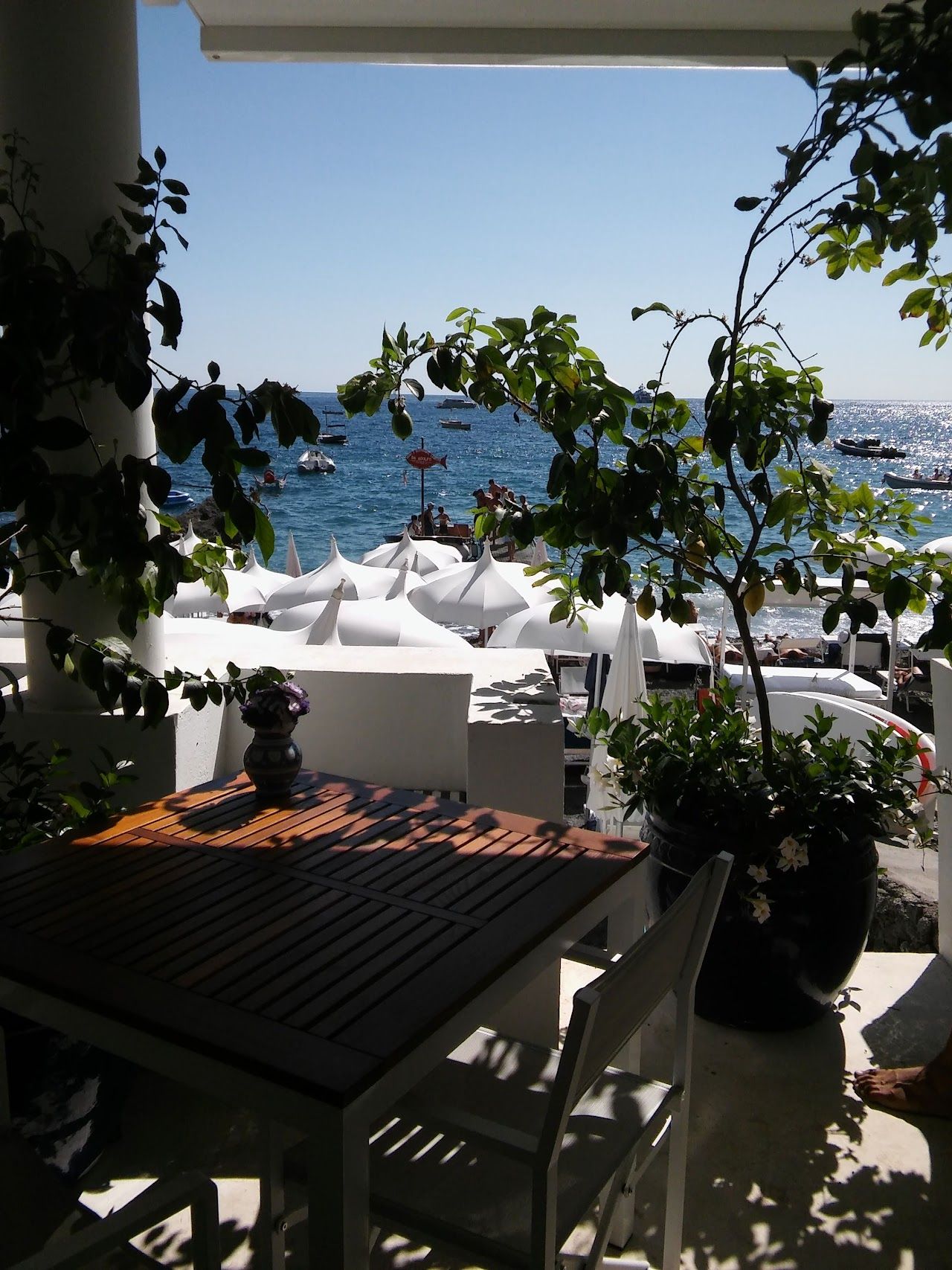 Wooden tables on the small beach at Da Adolfo reached by boat near Positano on the Amalfi Coast