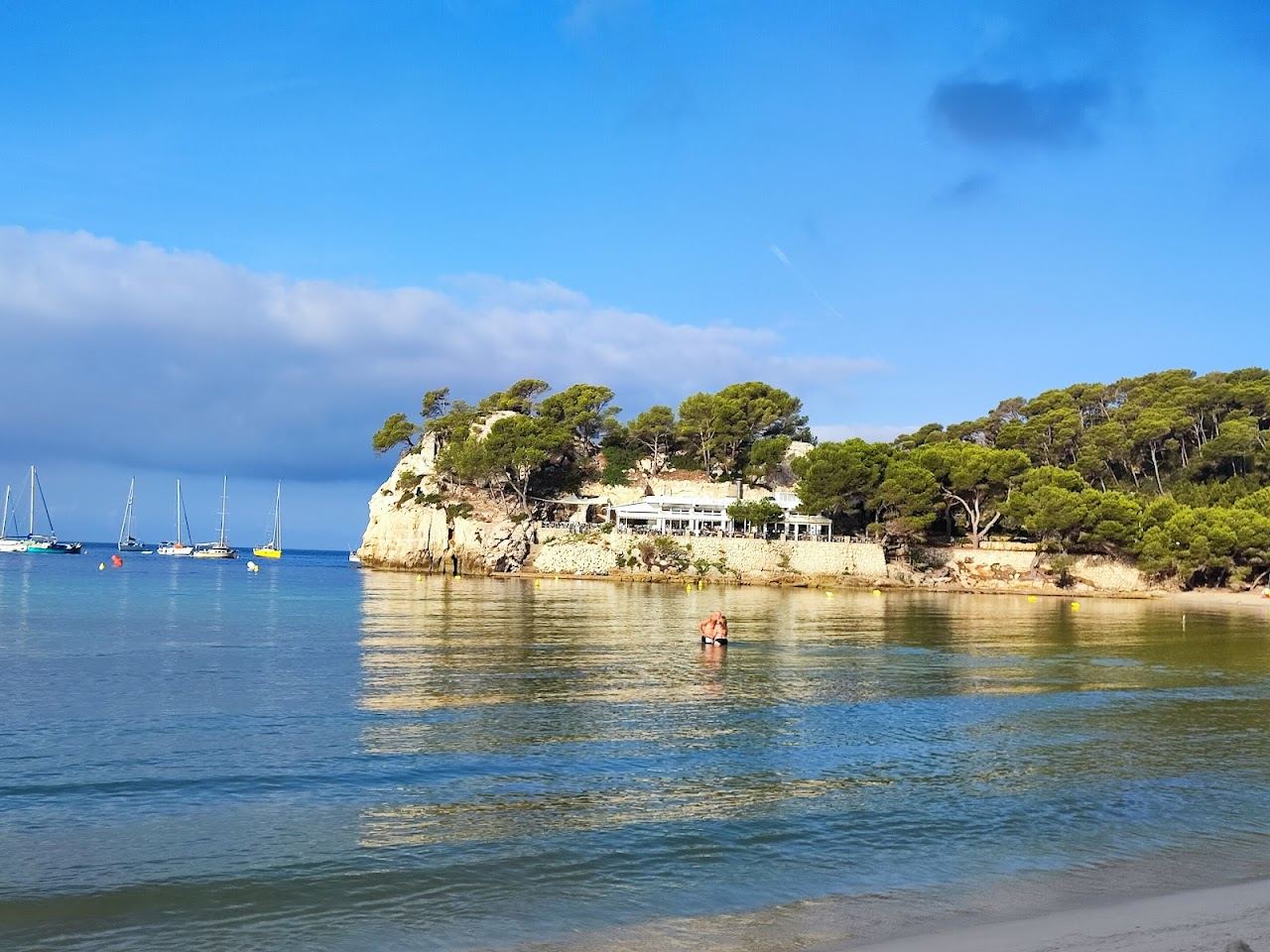 Calm turquoise water and pale sand at Cala Galdana in Menorca on a clear day