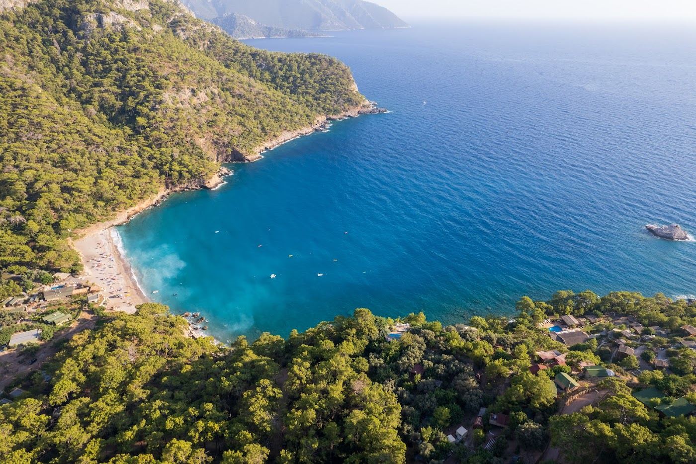 The wild forest backed bay of Kabak Beach with clear deep water below steep pine slopes south of Oludeniz near Faralya in Turkey