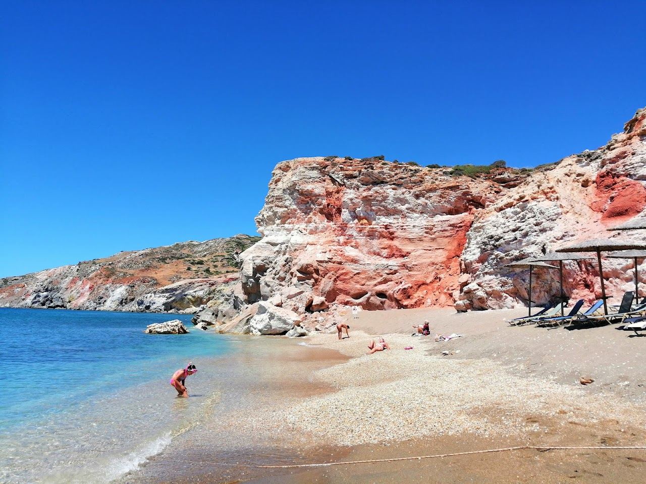 The broad volcanic beach of Paliochori below streaked red cliffs on the south coast of Milos