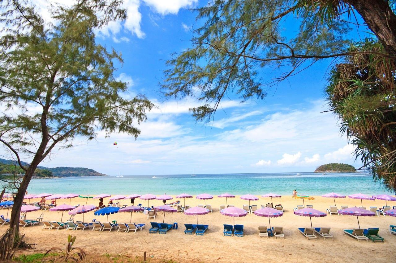 Long sweep of golden sand and warm sea on a beach in Phuket, Thailand