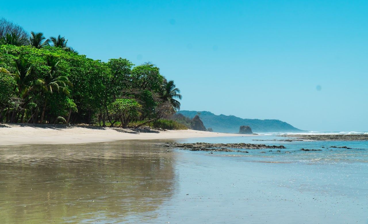 Wide dark gold sand and surfers under a golden sky at Playa Santa Teresa Costa Rica
