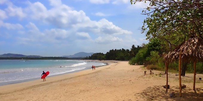 Palm fringed golden sand and gentle waves at Playa Tamarindo at sunset