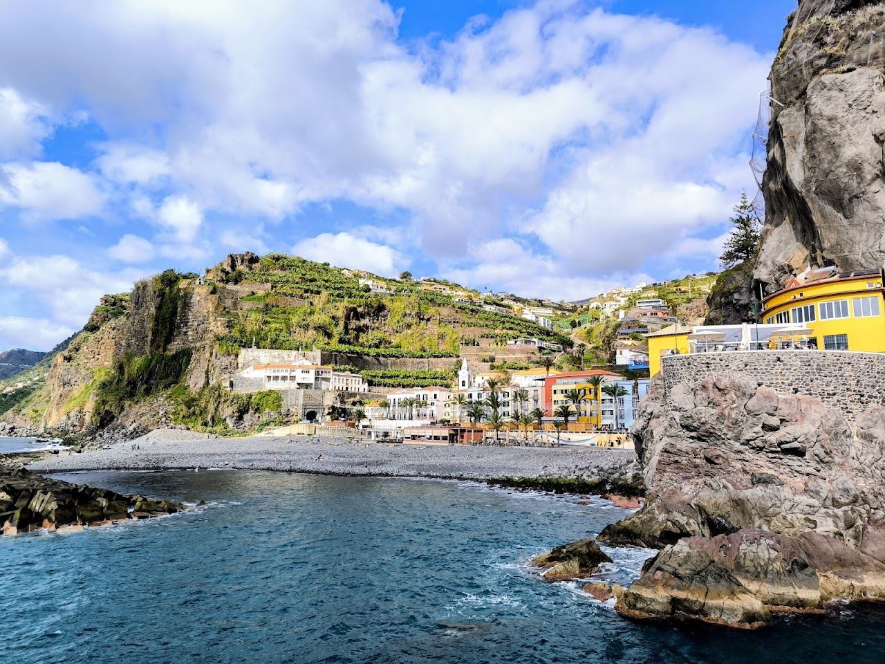 Sheltered pebble cove below cliffs in the sunny town of Ponta do Sol on the southwest coast of Madeira