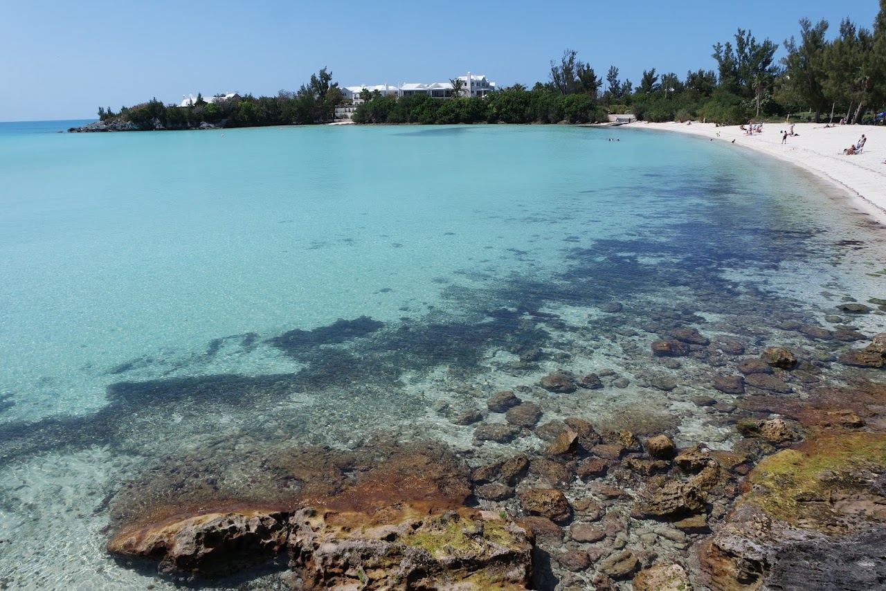 The wide shallow shore of Shelly Bay backed by trees and a park in Hamilton Parish Bermuda