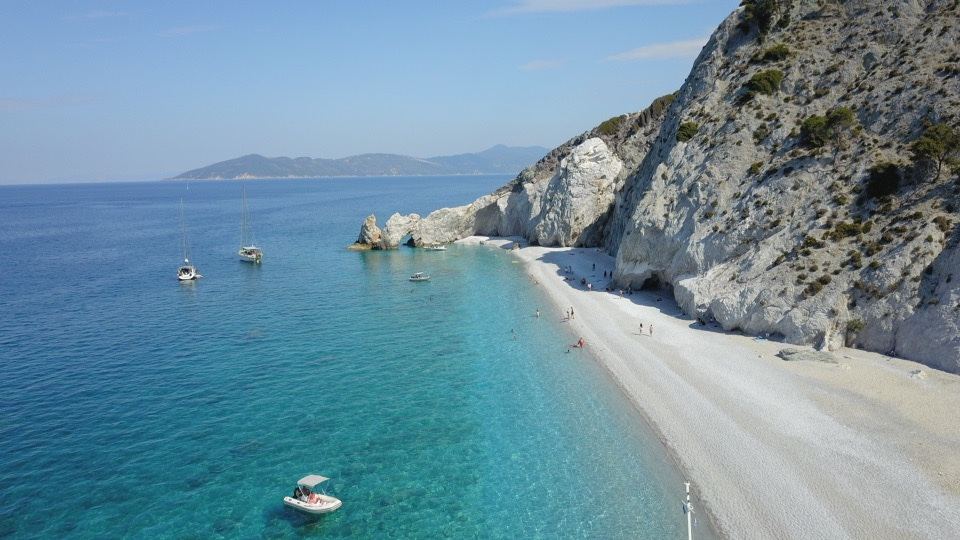 White pebble cove and clear water under tall cliffs at Lalaria beach on north Skiathos